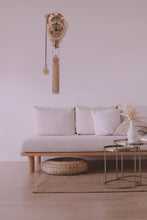 Load image into Gallery viewer, Assembled Vera clock shown mounted in modern white living room. White walls, white couch with wood accents and metallic round coffee table.